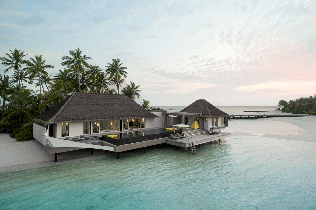 Aerial view of Cheval Blanc Randheli — overwater villas arranged across six private islets in the Noonu Atoll lagoon, a Jean-Michel Gathy composition.