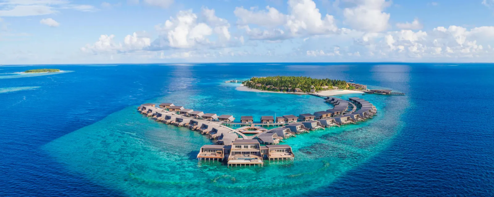 The St. Regis Maldives Vommuli Resort in Dhaalu Atoll — turtle-shell villa roofs and the whale-shark silhouette of the Whale Bar, by WOW Architects.